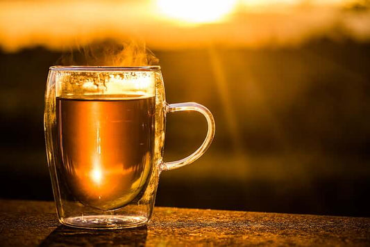 A cupp of tea with the sunrise in the background